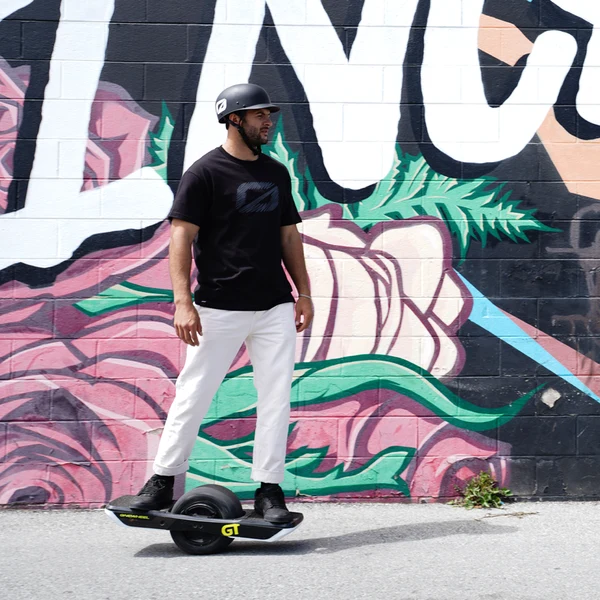 Marc en Onewheel GT en ville devant un mur de graffiti